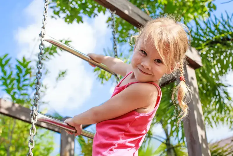 Mädchen klettert an einem Spielgerüst im Garten